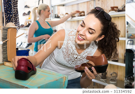 girl holding a picked pair of shoes in the boutique 31334592