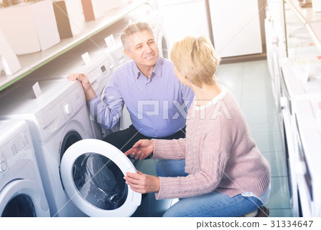Mature smiling couple choosing home washing machine Mature smiling couple choosing home washing machine 31334647