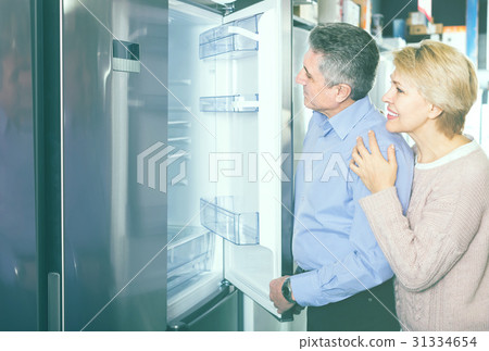 smiling mature married couple in shop of household appliances are choosing home modern refrigerator smiling mature married couple in shop of household appliances are choosing home modern refrigerator 31334654