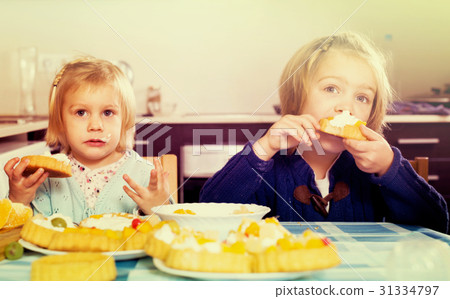 Two little girls enjoying pastry with cream Two little girls enjoying pastry with cream 31334797