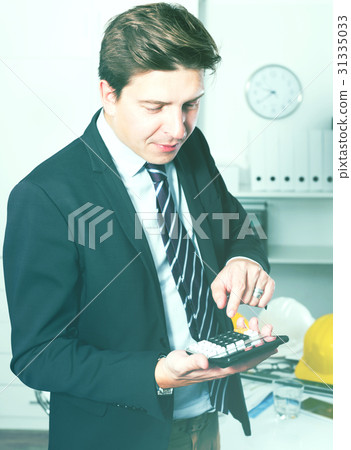 Man worker calculating in the office Man worker calculating in the office 31335033