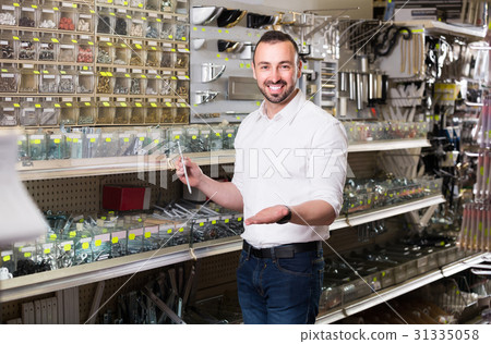 man standing next to showcase with various plastic rawlplugs and choosing one man standing next to showcase with various plastic rawlplugs and choosing one 31335058