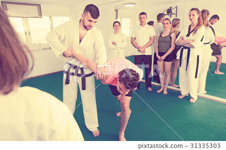Coach showing new submission hold in taekwondo class Coach showing new submission hold in taekwondo class 31335303