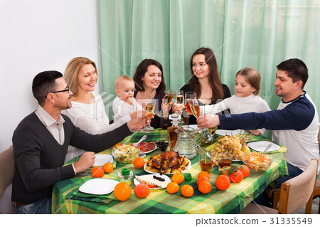 Positive multigenerational family sitting at holiday table Positive multigenerational family sitting at holiday table 31335549