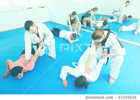 trainees sparring in pairs to practice new holds in taekwondo class trainees sparring in pairs to practice new holds in taekwondo class 31335616