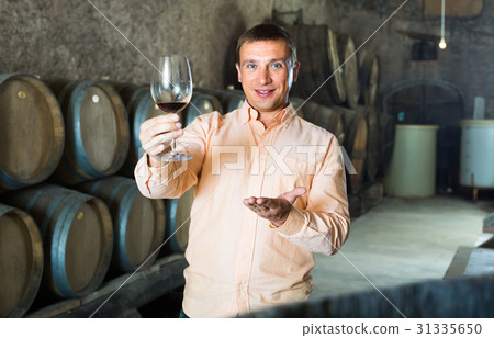 man with glass of wine in winery cellar. man with glass of wine in winery cellar. 31335650
