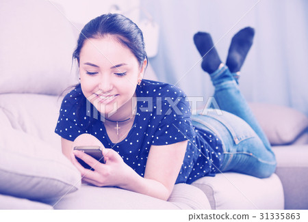 Happy woman on sofa with smartphone Happy woman on sofa with smartphone 31335863