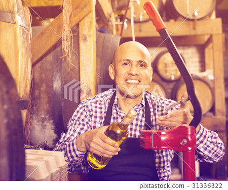 Mature male wine maker corking bottle of wine Mature male wine maker corking bottle of wine 31336322