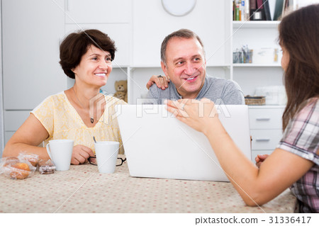 Daughter showing documents on laptop to her senior parents 31336417