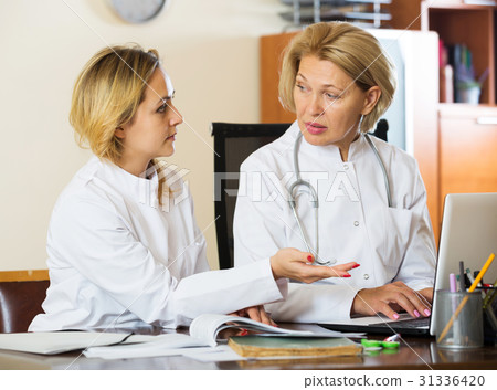 Family doctors therapeutists discussing difficult case in office Family doctors therapeutists discussing difficult case in office 31336420