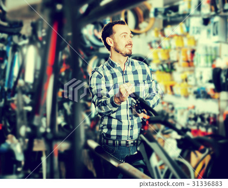Man considers bicycle handlebar in store Man considers bicycle handlebar in store 31336883