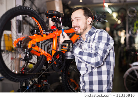 Man in sports workshop mounts bike using special tools 31336916