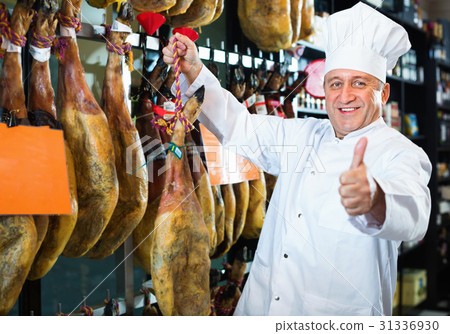 Portrait of mature shop man offering Spanish jamon 31336930