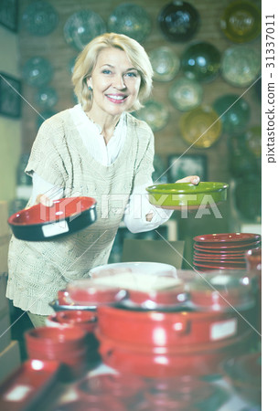 Female holding cookware at workshop and smiling Female holding cookware at workshop and smiling 31337011