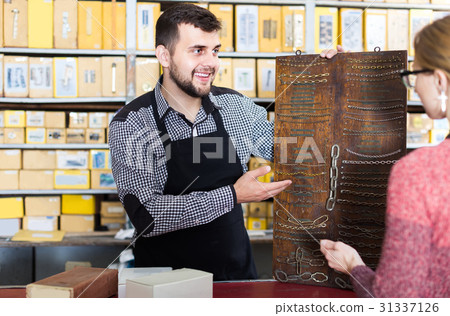 female shop assistant displaying assortment in houseware shop 31337126