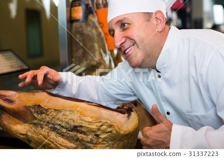 Elderly man seller showing iberian jamon 31337223