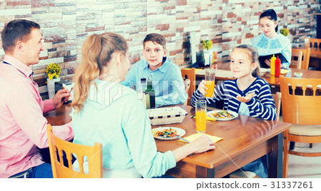 parents and smiling children chatting during dinner in family cafe parents and smiling children chatting during dinner in family cafe 31337261