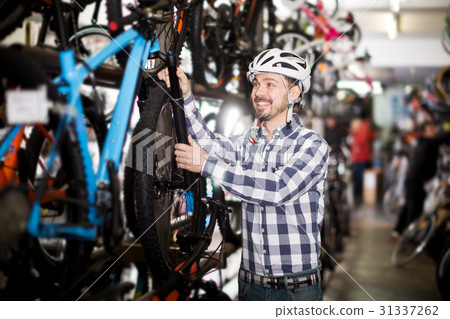 Man in helmet chooses convenient bike 31337262