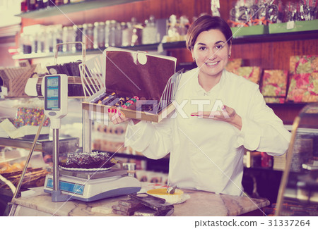 Shop assistant demonstrating box of chocolates Shop assistant demonstrating box of chocolates 31337264