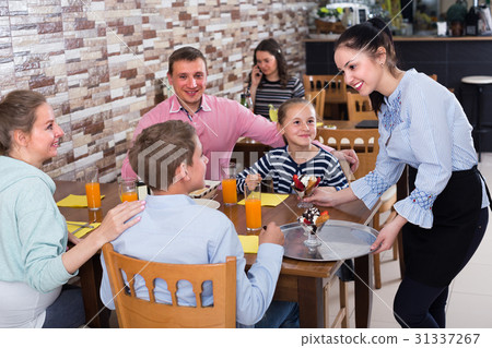 Young smiling wairtess is bringing delicious dessert to young visitors Young smiling wairtess is bringing delicious dessert to young visitors 31337267
