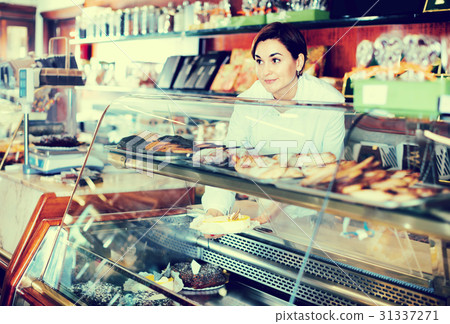 Female seller assisting in choosing dessert Female seller assisting in choosing dessert 31337271