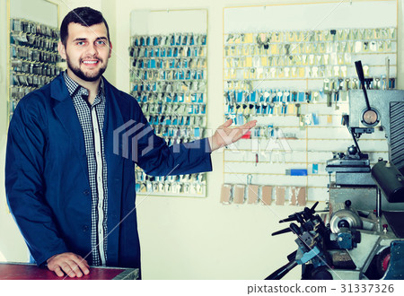 male worker showing his tools for making keys in workshop 31337326