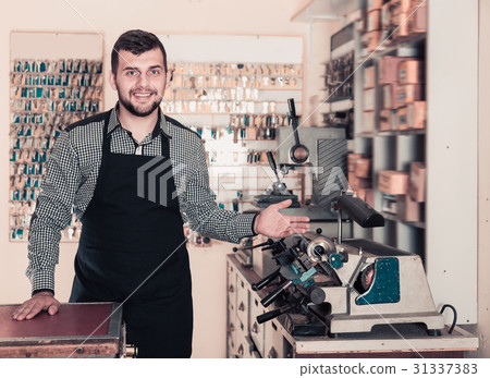 Worker demonstrating tools for making keys 31337383