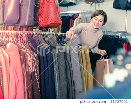Glad woman choosing turtleneck sweater 31337601