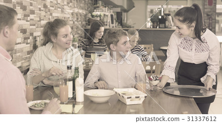 Young girl is bringing delicious dessert to young visitors Young girl is bringing delicious dessert to young visitors 31337612