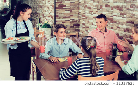 Young waitress serving family in family cafe 31337625