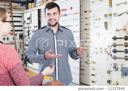 Assistant helping female customer to choose door handles 31337640