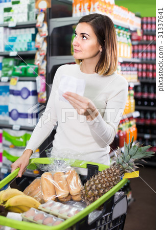 woman consulting shopping list in supermarket 31337641