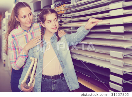 woman and girl shopping multicolored paper in art store 31337805