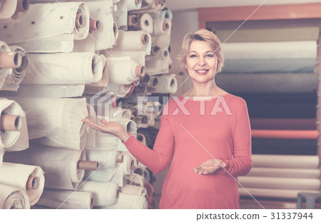 Female shop assistant demonstrating assortment at textile shop 31337944