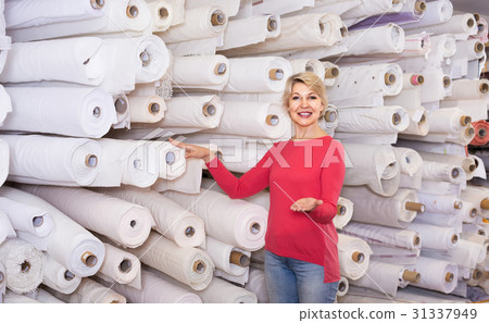 Female shop assistant demonstrating assortment at textile shop 31337949