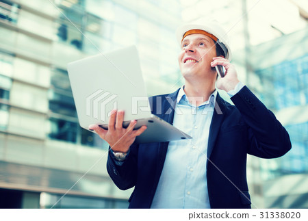 Smiling worker talking at mobile phone Smiling worker talking at mobile phone 31338020