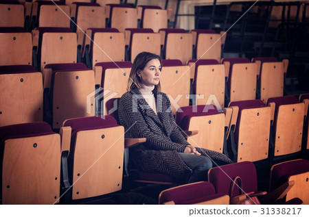 Lonely sad woman sitting in empty audience hall Lonely sad woman sitting in empty audience hall 31338217