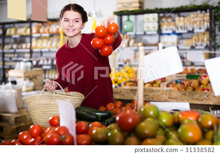 Portrait of satisfied young female customer selecting tomatoes in grocery Portrait of satisfied young female customer selecting tomatoes in grocery 31338582
