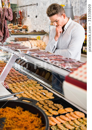 Young man choosing what kind of meat to buy Young man choosing what kind of meat to buy 31338609
