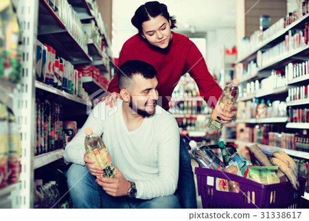 Customers choosing seed-oil in plactic packing at shop Customers choosing seed-oil in plactic packing at shop 31338617