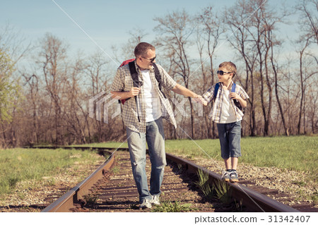 Father and son walking on the railway at the day time. Father and son walking on the railway at the day time. 31342407