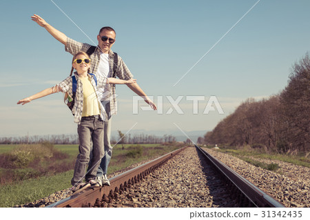 Father and daughter walking on the railway at the day time. 31342435