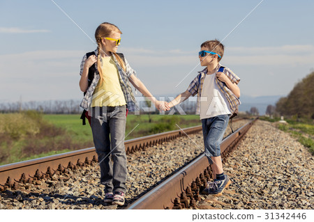 Happy brother and sister walking on the railway at the day time. 31342446