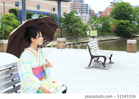 A young lady in a yukata sitting on an image bench in summer 31345536