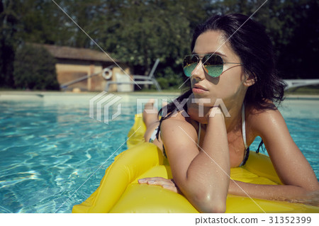 woman in bikini sunbathing on air mattress in the swimming pool woman in bikini sunbathing on air mattress in the swimming pool 31352399
