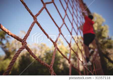 Boy climbing a net during obstacle course Boy climbing a net during obstacle course 31357118
