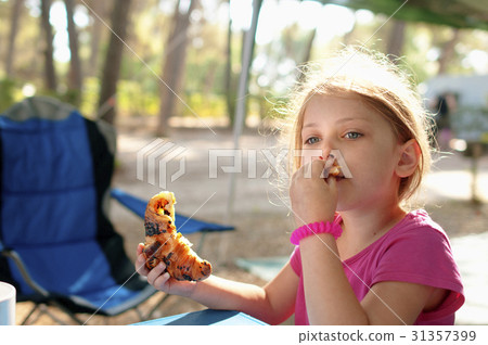Little caucasian girl having a breakfast outdoor 31357399