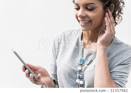 Cheerful young lady is standing with smartphone in Cheerful young lady is standing with smartphone in 31357982