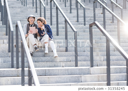 Positive girl and boy sitting on steps with smile Positive girl and boy sitting on steps with smile 31358245