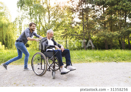 Hipster son running with disabled father in 31358256
